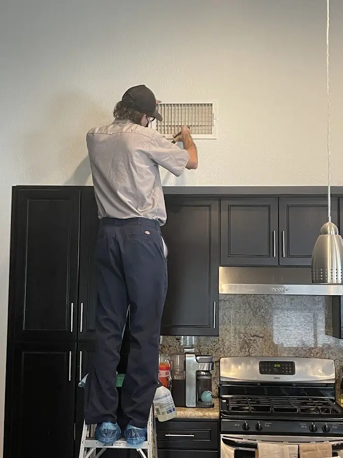Technician inspecting an air vent during HVAC service in Easton